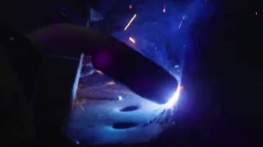 Kapalı çekimde, bir adam yaydan çıkan çelik yelek için plaka kaynatıyor. Ev yapımı zırh plakası. Fabrika işçisi metali kaynaklıyor. Adam kaynak yapıyor. Kaynak makinesi kullanarak argon veya elektrot ile kaynak yapmak. Kıvılcım ve
