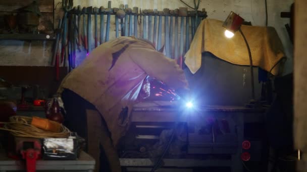 一个人从弹簧上焊钢板作为防弹衣.自制的装甲板。工厂工人焊接金属.那个人正在焊接.用氩或电极焊接,用焊机焊接.火花和闪光飞扬 — 图库视频影像