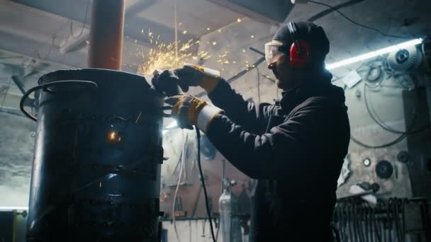 Montáž kovových konstrukcí, výroba domácího topení profesionálním pracovníkem pomocí brusky. Broušení s hladkým zařízením pro ocelové kovy, železo, jiskry v těžkém průmyslu továrny — Stock video