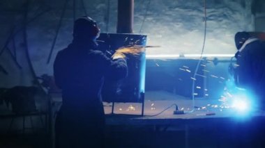 Metal yapılar monte etmek, öğütme makinesi kullanan profesyonel bir işçi tarafından ev yapımı ısıtıcı yapmak. Çelik metal, demir ve ağır sanayi fabrikasında kıvılcımlar saçan pürüzsüz ekipmanlarla öğütme işi