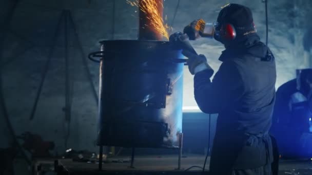 Het assembleren van metalen structuren, het maken van een zelfgemaakte kachel door een professionele werknemer met behulp van een slijpmachine. Slijpen met gladde apparatuur voor staal, ijzer, vonken in een zware industrie fabriek — Stockvideo