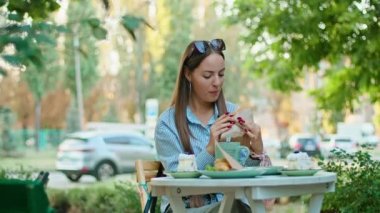 Yazlık kafede sandviç yiyen genç ve mutlu bir kadın..