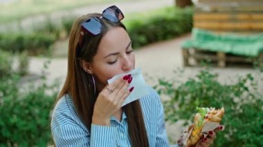 Yazlık kafede sandviç yiyen genç ve mutlu bir kadın..