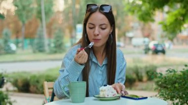 Bir kafede genç ve mutlu bir kadın kek yiyor.