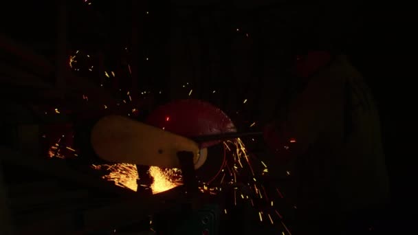 Close-up, Een man snijdt een metalen onderdeel voor een kogelvrij vest uit veren. zelfgemaakte pantserplaat. Fabrieksarbeider snijdt metaal. Hij is aan het snijden. snijden met een industriële slijpmachine. Vonken en flitsen vliegen — Stockvideo