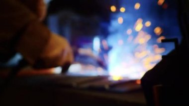 Kapalı çekimde, bir adam yaydan çıkan çelik yelek için plaka kaynatıyor. Ev yapımı zırh plakası. Fabrika işçisi metali kaynaklıyor. Adam kaynak yapıyor. Kaynak makinesi kullanarak argon veya elektrot ile kaynak yapmak. Kıvılcım ve