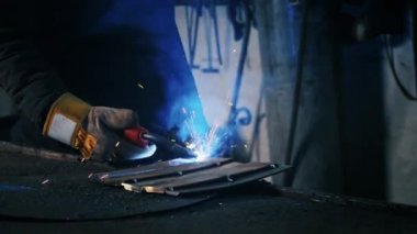 Fabrikadaki yorgun bir işçinin fotoğrafı. Çelik yapı kaynaklama, profesyonel işçiler tarafından ev yapımı zırh levhası, kaynak makinesi, demir kaynaklama, kapalı alanda ağır sanayi fabrikalarında kıvılcımlar. çelişki