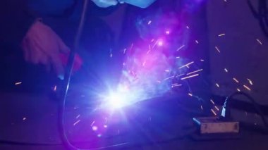 Yakın plan, fabrikada yorgun bir işçinin fotoğrafı. Çelik yapı kaynaklama, profesyonel işçilerin ev yapımı zırh plakası kaynak makinesi, demir kaynaklama, ağır sanayi fabrikasında kıvılcımlar.