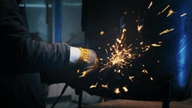 Metal yapılar monte etmek, öğütme makinesi kullanan profesyonel bir işçi tarafından ev yapımı ısıtıcı yapmak. Çelik metal, demir ve ağır sanayi fabrikasında kıvılcımlar saçan pürüzsüz ekipmanlarla öğütme işi