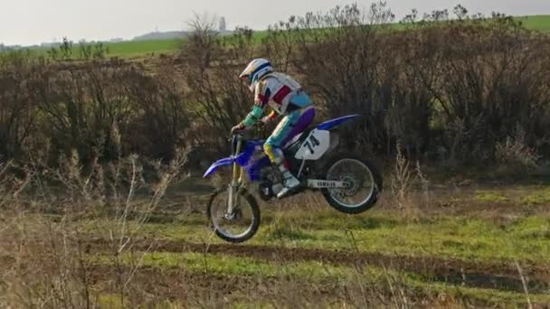 Kryvyi Rih, Ukraine - October, 24, 2021 Shot of the professional motocross rider on his motorcycle on the extreme terrain track. Biker flying on a motocross motorcycle. Construction background and sky — Wideo stockowe