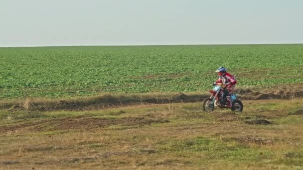 Kryvyi Rih, Ukraine - October, 24, 2021 Shot of the professional motocross rider on his motorcycle on the extreme terrain track. Biker flying on a motocross motorcycle. Construction background and sky — Video