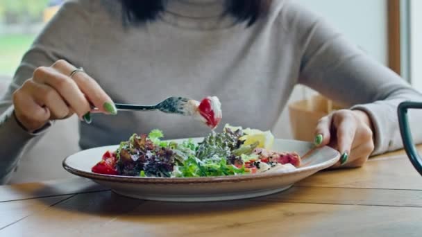 两个年轻快乐的女人享受着美味的鸡肉沙拉，西红柿和克罗顿，在炎热的夏天，用叉子在一个美丽凉爽的地方吃. — 图库视频影像
