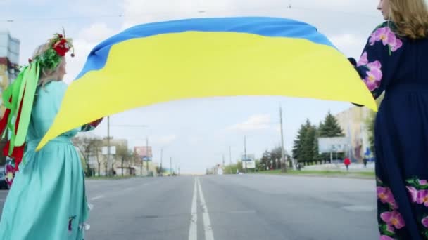 Two happy woman rejoices and walk along the road with the flag of ukraine. Weekend stroll with a smile at sunset. woman and spring. — стоковое видео