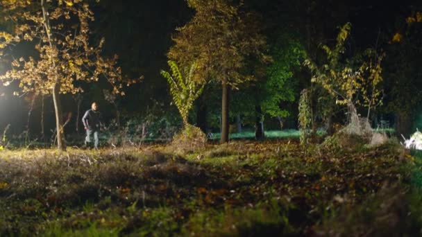 In der Filmaufnahme läuft ein Mann durch einen dunklen Wald, eine gruselige Zombie-Frau rennt aus der Dunkelheit und greift an. horror. halloween. Das wirkliche Böse. — Stockvideo