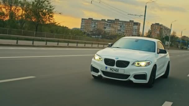 Krivoy Rog, Ukrajina - 05.07.2022: Rolling shot of a BMW 3 series, German car, luxury sports sedan driving on a highway at sunset, close-up view