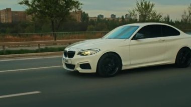 BMW 3 serisi, Alman arabası, gün batımında otoyolda giden lüks spor sedan, yakın çekim.