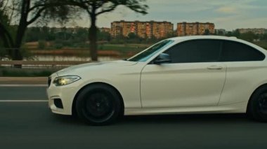 BMW 3 serisi, Alman arabası, gün batımında otoyolda giden lüks spor sedan, yakın çekim.