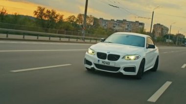 BMW 3 serisi, Alman arabası, gün batımında otoyolda giden lüks spor sedan, yakın çekim.