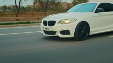 BMW 3 serisi, Alman arabası, gün batımında otoyolda giden lüks spor sedan, yakın çekim.