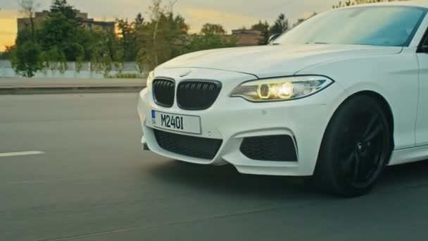 Krivoy Rog, Ukraine - 05.07.2022: Rolling shot of a BMW 3 series, German car, luxury sports sedan driving on a highway at sunset, close-up view — Stockvideo