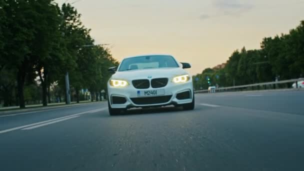 Krivoy Rog, Ucrania - 05.07.2022: Rolling shot of a BMW 3 series, German car, luxury sports sedan driving on a highway at sunset, close-up view — Vídeo de stock
