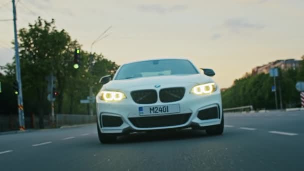 Krivoy Rog, Ucrânia - 05.07.2022: Filmagem de um BMW série 3, carro alemão, sedan esportes de luxo dirigindo em uma estrada ao pôr do sol, vista de close-up — Vídeo de Stock