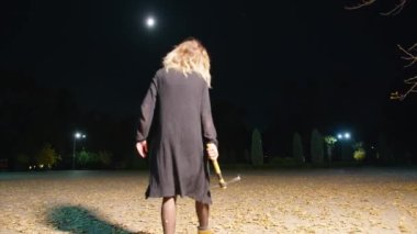 cinematic shot, creepy zombie woman with hammer walks in the night park. horror. halloween. real evil.