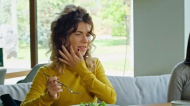 two young happy women enjoy delicious salad of chicken, tomato and croutons, eat it with a fork in a beautiful cool place in hot summer.