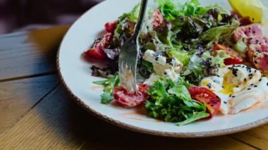 two young happy women enjoy delicious salad of chicken, tomato and croutons, eat it with a fork in a beautiful cool place in hot summer.