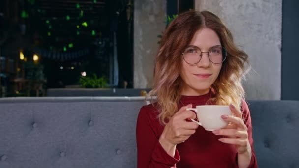 Χαλαρός χαμογελαστή ικανοποιημένη γυναίκα με κόκκινο φλιτζάνι καφέ στέκεται στο τέλος του δρόμου απολαμβάνοντας μια ηλιόλουστη μέρα — Αρχείο Βίντεο