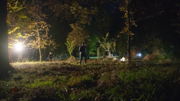 In der Filmaufnahme läuft ein Mann durch einen dunklen Wald, eine gruselige Zombie-Frau rennt aus der Dunkelheit und greift an. horror. halloween. Das wirkliche Böse. — Stockvideo