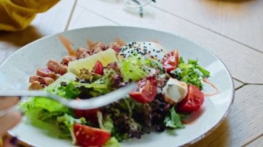 İki genç ve mutlu kadın leziz tavuk, domates ve kızarmış ekmek salatasının tadını çıkarıyorlar. Sıcak yaz mevsiminde güzel bir yerde çatalla yiyorlar.