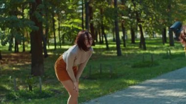 Şehir parkının arka planında poz veren mutlu genç kız arkadaşı fotoğrafçıya. gençlik ve güzellik