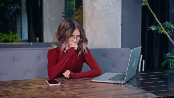 可怜的疲倦的年轻女人坐在桌旁 手里拿着电话和电脑 工作时间 休息和工作 — 图库视频影像