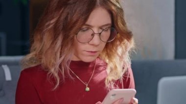 Masasında bilgisayar ve telefonla oturan bir kadın..