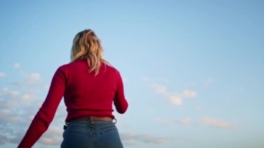 Genç bir kadın gün batımında dağ tepelerindeki bir telefonla yürüyüş sonrası rahatlamak için video iletişimi kurmaktan mutluluk duyar. Doğadaki diğer bir kişi, dağlarda.