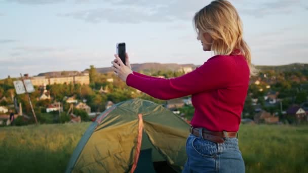 一个年轻的女人喜欢在日落时用电话在山上进行视频交流 在徒步旅行后放松一下 一个人在自然界中的休息 在山里 — 图库视频影像