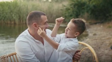 Dört kişilik mutlu bir aile göletin kenarında eğleniyor, çocuklar anne ve babalarıyla eğleniyor.