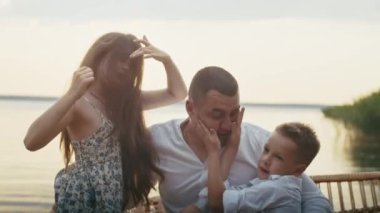 Dört kişilik mutlu bir aile göletin kenarında eğleniyor, çocuklar anne ve babalarıyla eğleniyor.