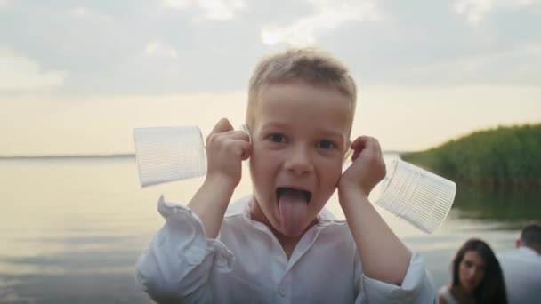 Neşeli Bir Çocuk Havuza Girer Kulaklarına Bardak Dayar Yüzünü Buruşturur — Stok video