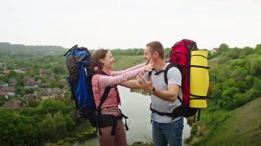 Dağlarda yaşayan mutlu çift, erkek ve kadın, tatil yeri aramak için seyahat ediyorlar. Sevinçten havalara uçarlar, güzel bir manzaranın arka planında durarak. Dağlarda tatil
