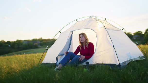 一个年轻的女人在日落时高兴地在山上搭起一个帐篷 在远足之后休息 喝热茶的女人 一个人在自然界中的休息 在山里 — 图库视频影像