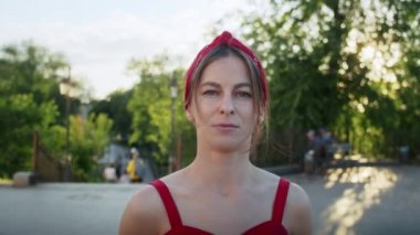 Kırmızı elbiseli mutlu kız parkta yürüyor, sokağın batan güneşinin tadını çıkarıyor, yaz yaşam tarzı.