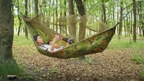 Счастливая Азиатская Женщина Вместе Дочерью Смотреть Кино Гамаке Насладиться Отдыхом — стоковое видео