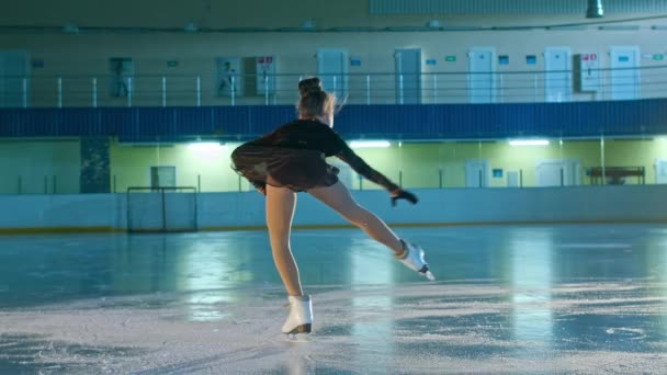 年轻女子花样滑冰选手在冰上滑冰 她做不同的动作和旋转轮盘 比赛开始前在溜冰场进行舞蹈训练 技术概念 — 图库视频影像