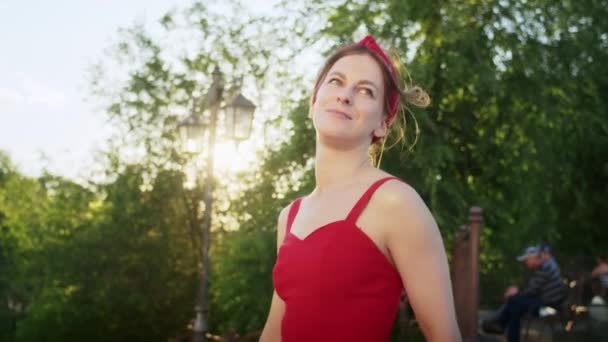 穿着红衣服的快乐女孩在公园里散步 享受夕阳西下的街道 享受夏日的生活 — 图库视频影像