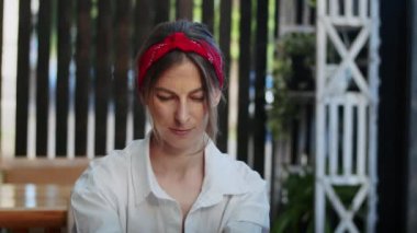 Mutlu kız telefonla konuşuyor ya da video izliyor, sokak kafesinde, yaz zamanı rahat bir yaşam sürüyor ve eğleniyor.