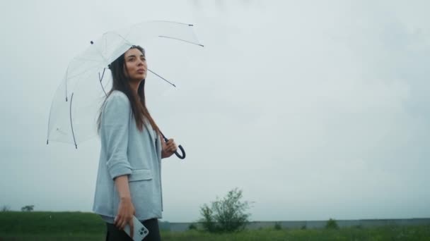 悲しいアルメニア人女性が傘を持って雨の中を歩く 彼女はこの天気を楽しんで — ストック動画
