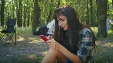 Tatilden zevk alan mutlu bir kadın, görüntülü konuşma, telefonla film izleme, Forest City Park 'taki çadırda dinlenme. yaz kampı