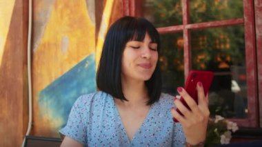 Mutlu bir kadın telefonla ya da video ile iletişim kurar, sıcak yaz aylarında açık hava yazlık kafede dinlenmeyi sever.